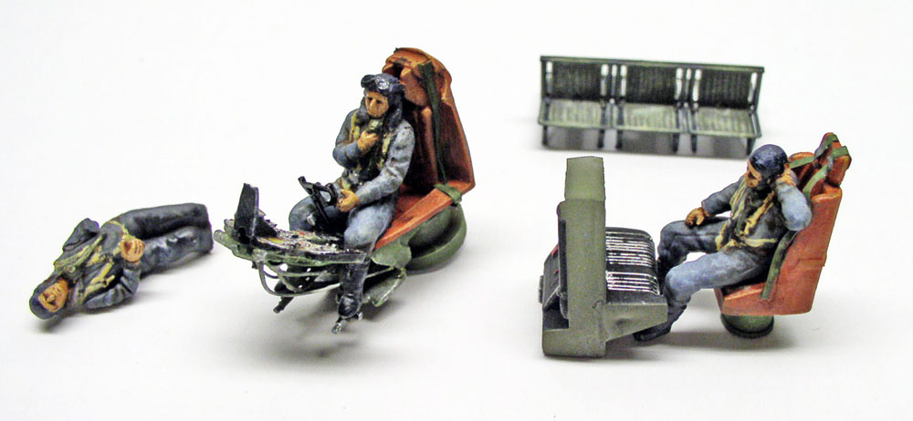 Figurines d'équipage peintes assises sur sièges et pièces de maquette détaillées sur fond blanc