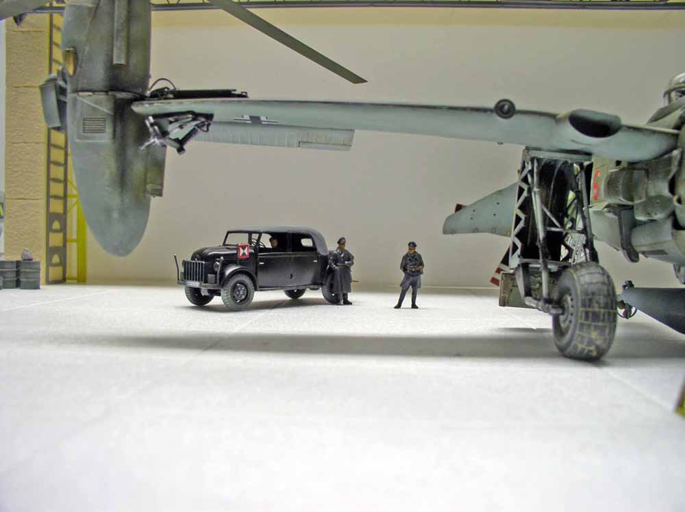 Diorama de hangar avec voiture noire, deux figurines d'officiers et avion militaire gris
