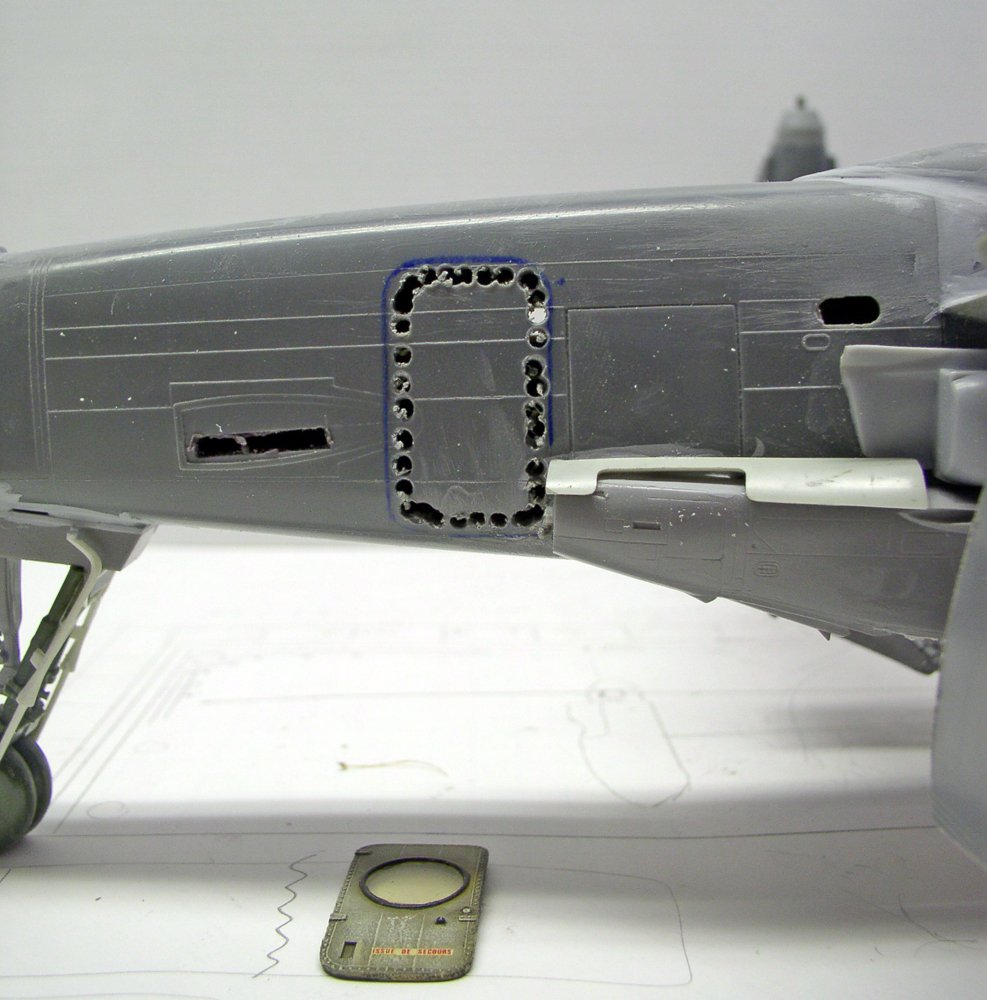 Fuselage gris de maquette d'avion avec ouverture percée de trous pour découper un nouveau panneau