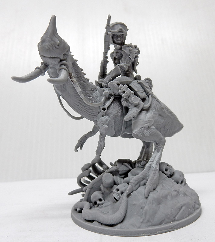 Figurine grise non peinte d'une cavalière chevauchant une créature reptilienne sur socle orné de crânes