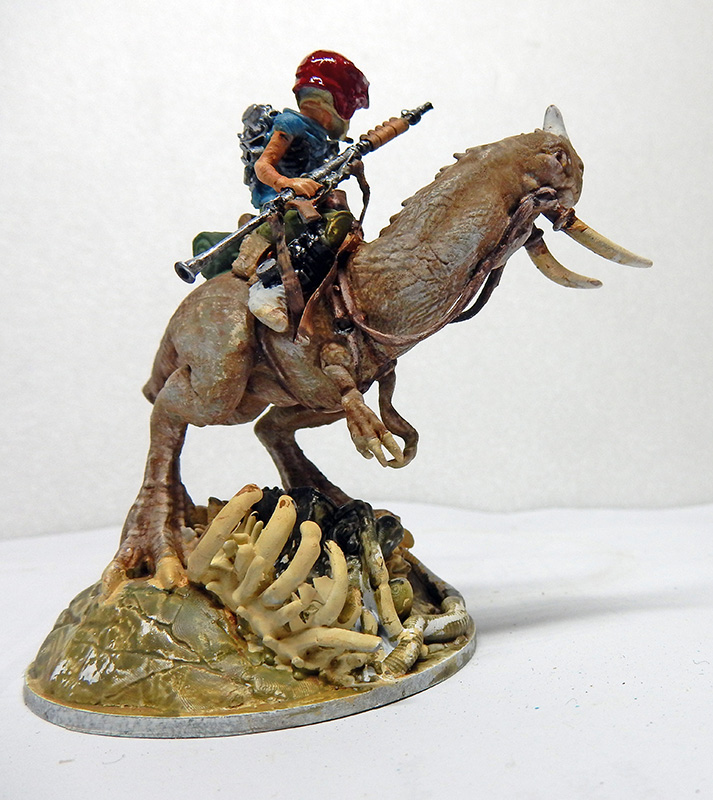 Figurine peinte d'un cavalier armé chevauchant une créature reptilienne à défenses sur un socle d'ossements