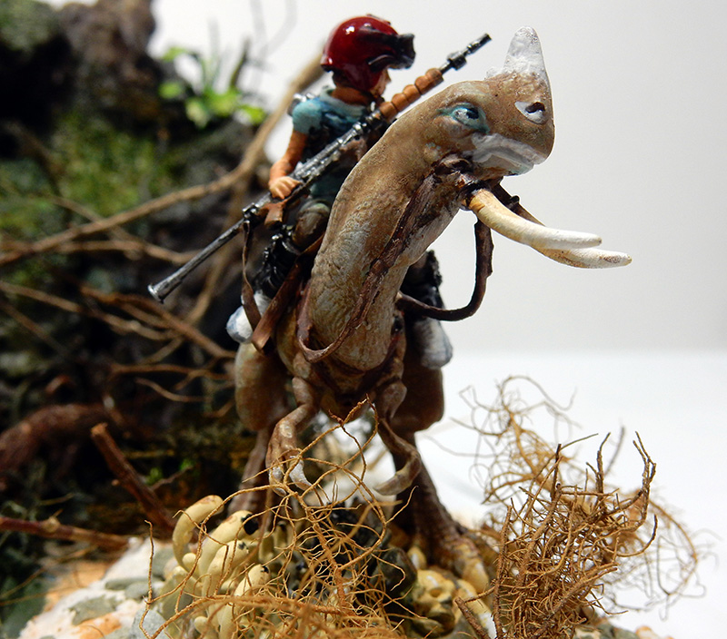 Figurine de cavalier armé chevauchant une créature à défenses dans un diorama de maquettisme