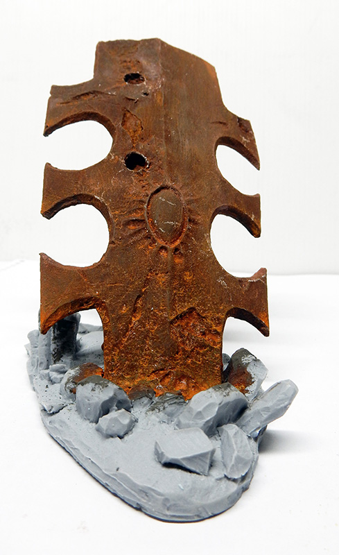 Maquette d'aile de dragon texturée effet rouille brun-orangé sur socle rocheux gris