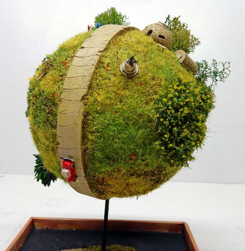 Diorama sphérique du planète Kaio avec route, végétation verte et petites maisons miniatures