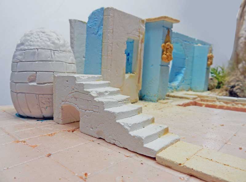 Maquette d'un décor méditerranéen avec escalier blanc, dôme et murs bleus en construction