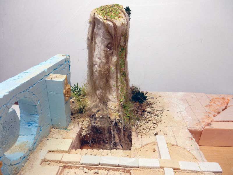 Maquette en construction d'un tronc d'arbre avec racines, végétation et muret de pierre bleue