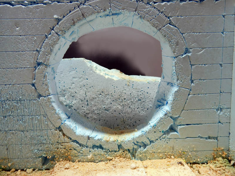Ouverture circulaire creusée dans un mur de maquette imitant du béton fissuré