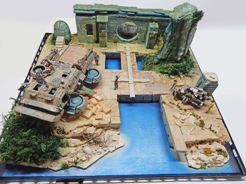 Diorama de maquettisme avec véhicule blindé, ruines antiques, bassins d'eau bleue et figurines de soldats