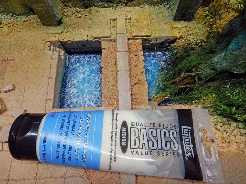 Tube de gel médium brillant Liquitex posé sur une maquette de canal d'eau