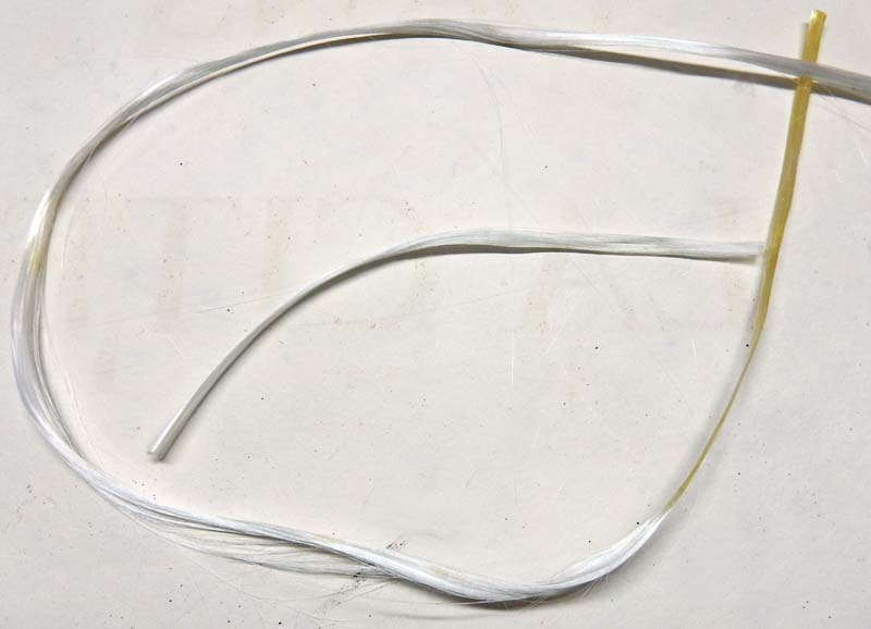 Fibres de fil blanc et brin plastique jaune disposés en boucle sur fond clair