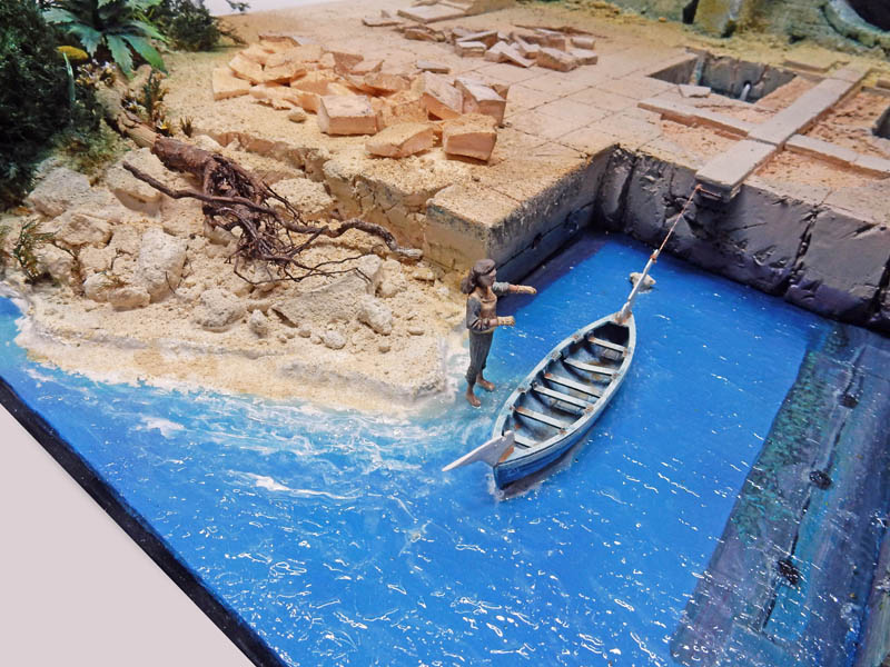 Diorama de maquettisme avec barque sur l'eau bleue, personnage, ruines antiques et rivage sablonneux