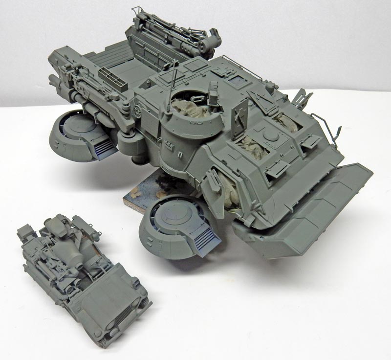 Maquette de véhicule blindé gris non peint accompagnée d'un petit véhicule militaire en construction