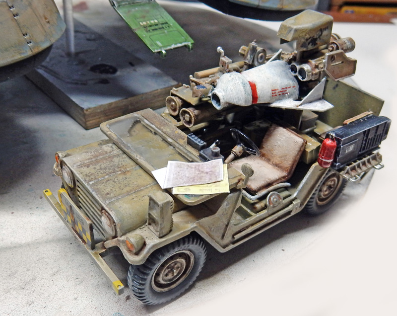 Maquette de jeep militaire portant un lance-missile, patine usée, sur fond d'atelier