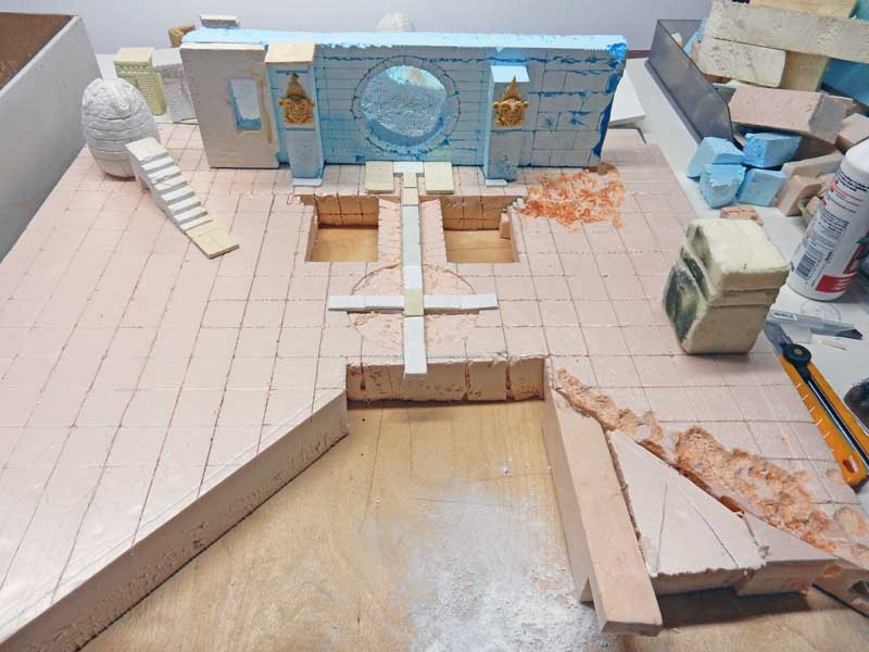 Maquette en polystyrène d'un décor en construction avec mur bleu, escalier et sol dallé
