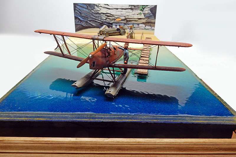 Diorama d'hydravion biplan sur l'eau près d'un ponton avec décor de falaise