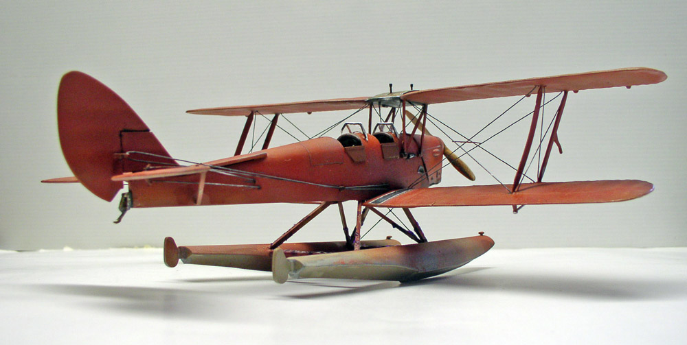 Maquette de biplan hydravion rouge sur flotteurs, vue trois quarts sur fond neutre