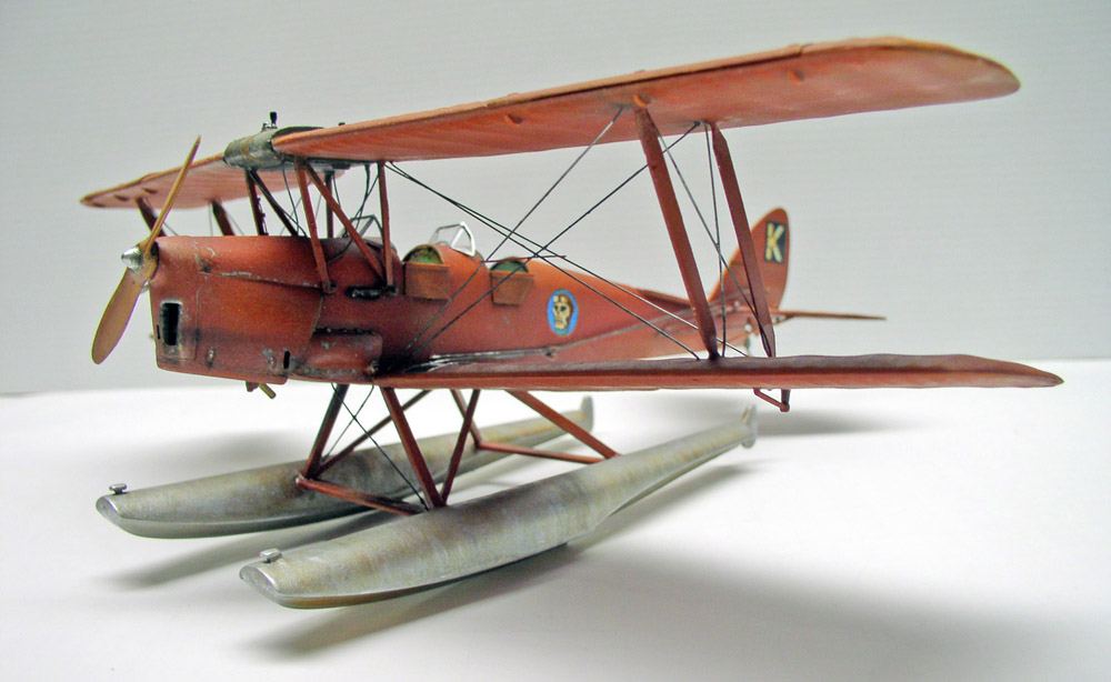 Maquette de biplan hydravion rouge sur flotteurs, haubanage détaillé, fond neutre
