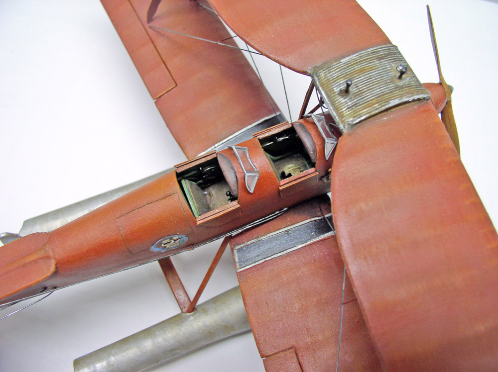 Gros plan sur les deux cockpits ouverts d'un biplan bois, haubans et capot moteur