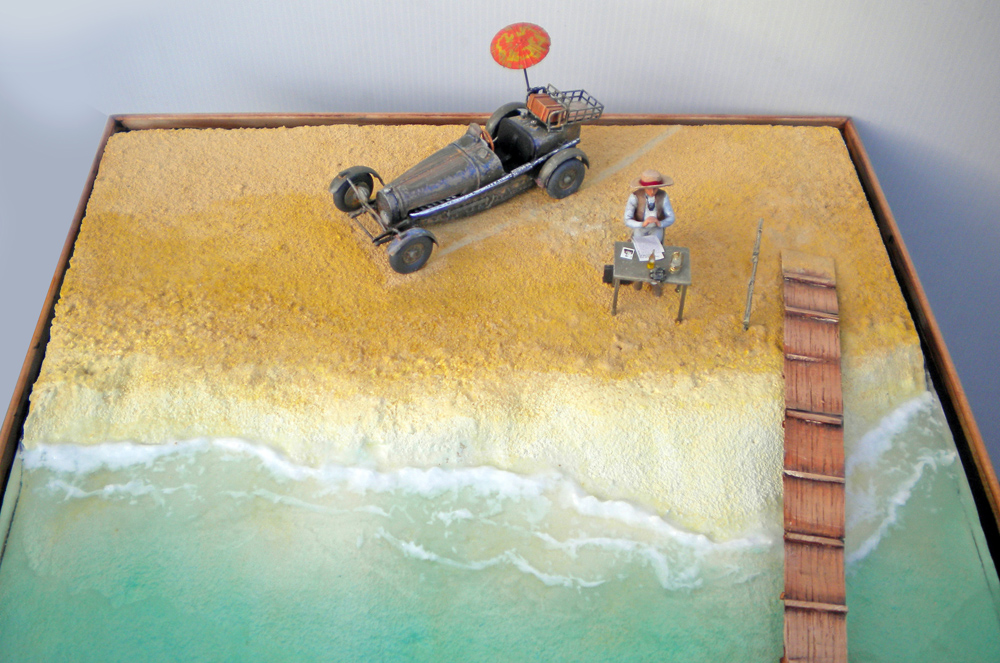 Diorama de plage avec voiture de course ancienne, personnage attablé sous parasol et ponton