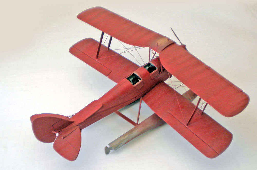 Maquette de biplan biplace rouge vue de trois quarts arrière sur fond neutre
