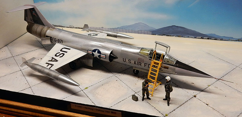 Diorama d'un F-104 Starfighter argenté sur tarmac vietnamien avec échelle et deux figurines