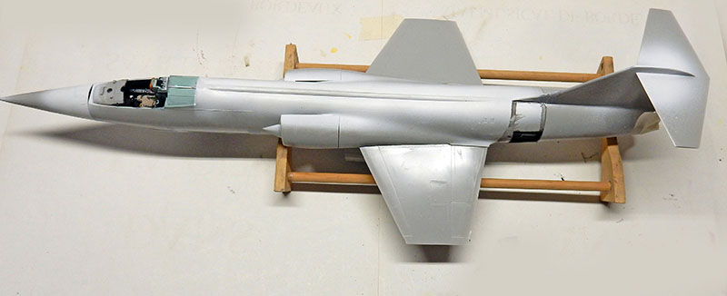 Fuselage du F-104 en apprêt gris sur berceau de montage, cockpit ouvert