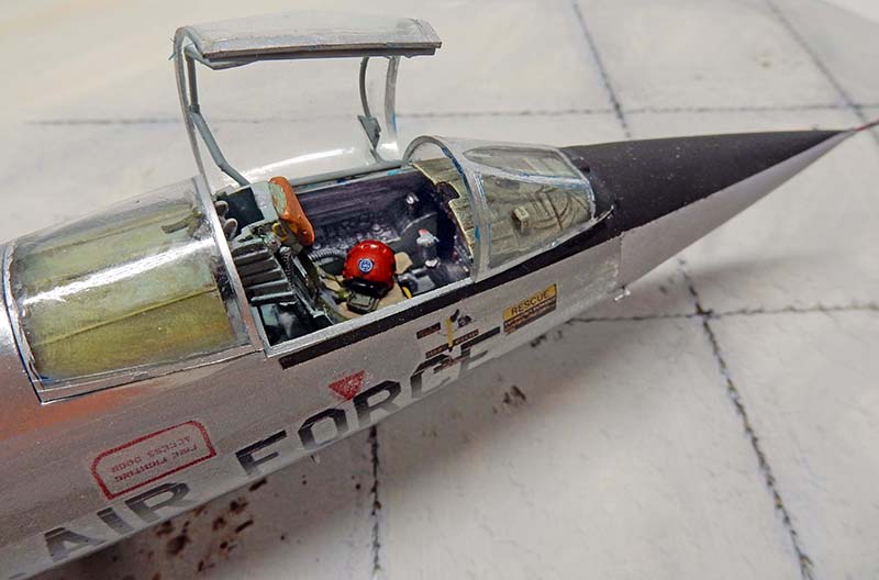 Gros plan sur le cockpit ouvert d'un F-104 Starfighter, pilote casqué rouge installé