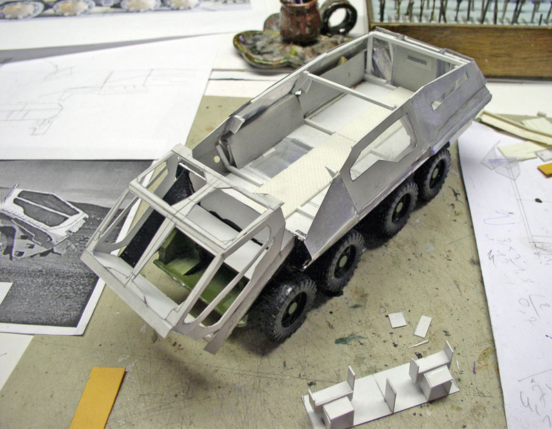 Maquette en construction d'un véhicule blindé huit roues en carton gris sur plan de travail