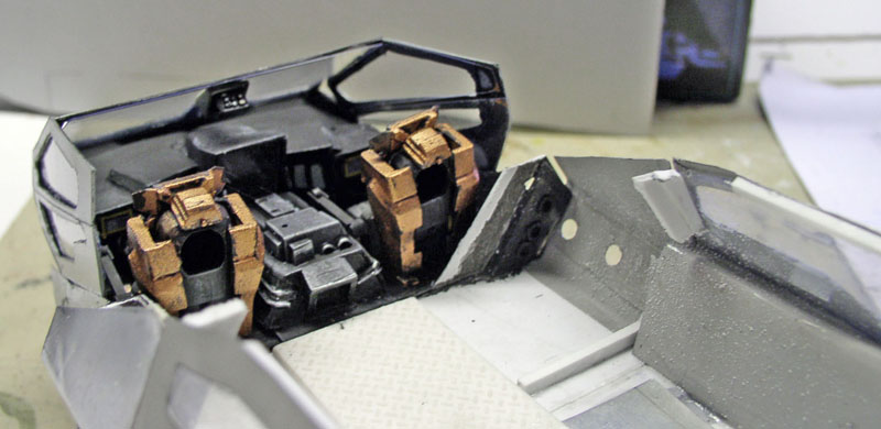 Intérieur de maquette avec deux sièges baquets ocre et cockpit gris en cours de montage