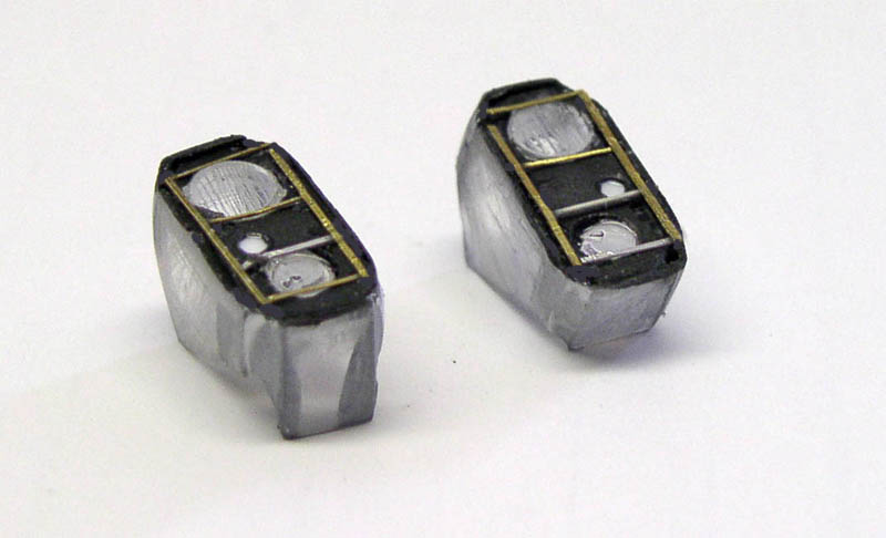 Deux blocs optiques de phares miniatures en métal avec encadrements laiton, vue rapprochée