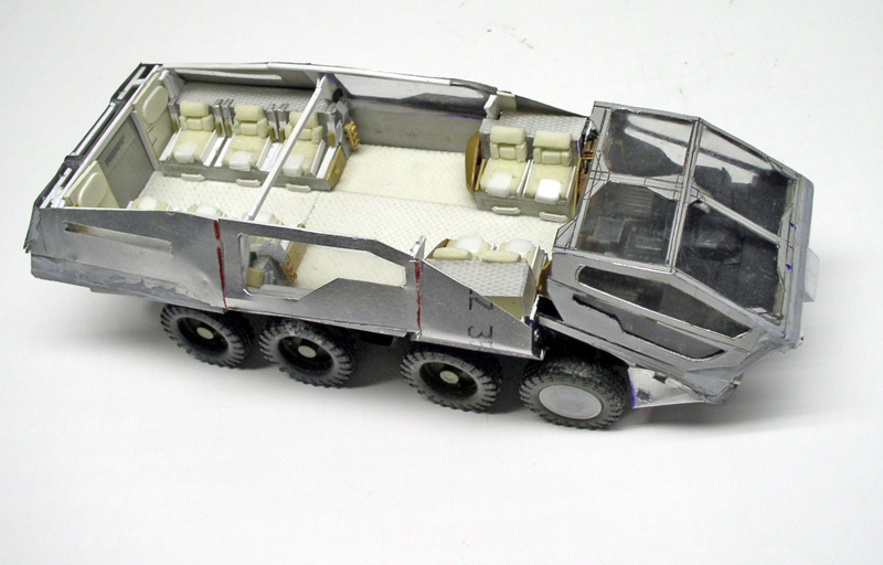 Maquette de véhicule blindé huit roues en métal nu avec habitacle ouvert montrant sièges et cabine vitrée
