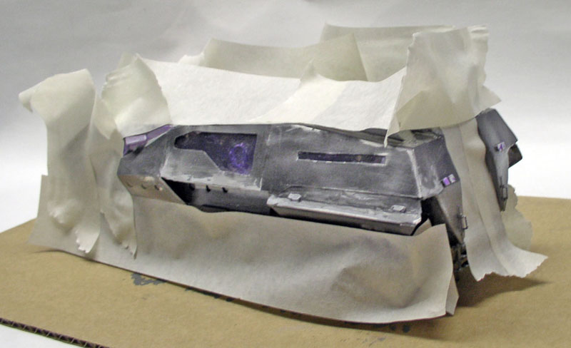 Maquette de véhicule gris peinte, protégée par du ruban de masquage sur un carton
