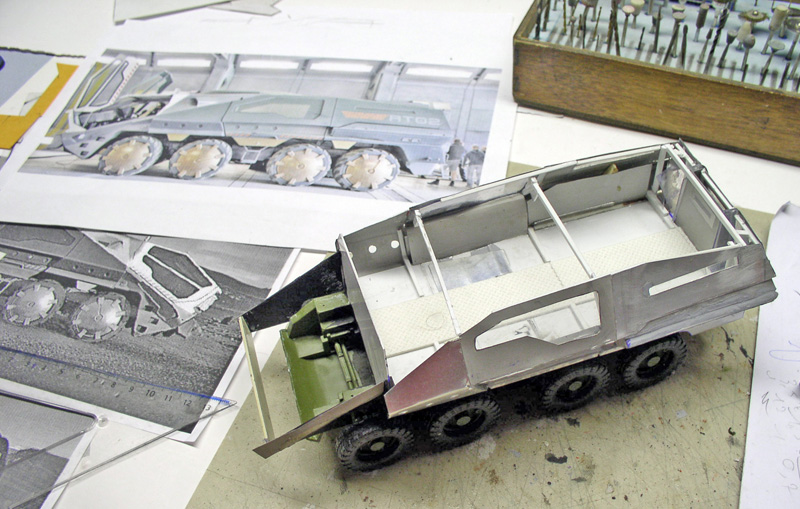 Maquette de véhicule blindé à huit roues en construction posée près des plans de référence