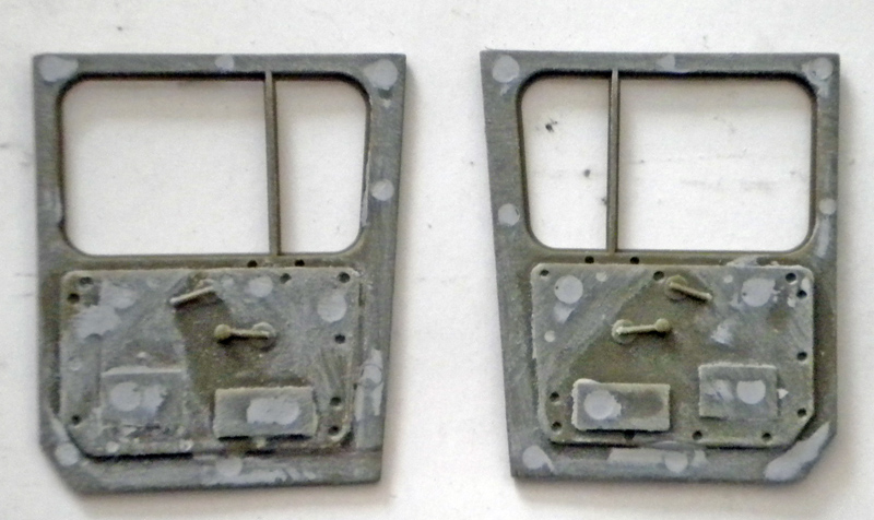 Deux portières de maquette en résine grise avec poignées et vitres, posées côte à côte