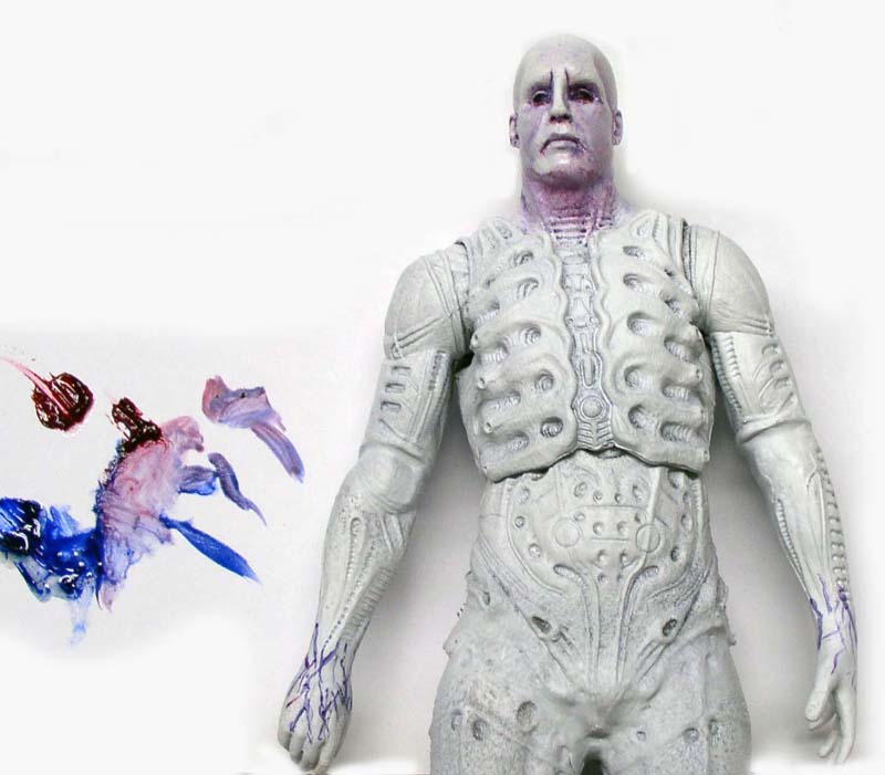 Figurine Prometheus Neca peinte en blanc à côté de mélanges de peinture bleue et rouge