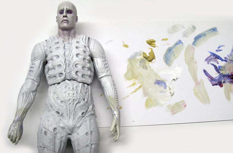 Figurine Ingénieur Prometheus blanche à côté d'une palette de peintures mélangées