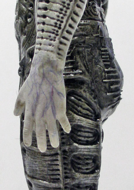 Détail peint de la main pâle veinée et du corps biomécanique de la figurine Prometheus
