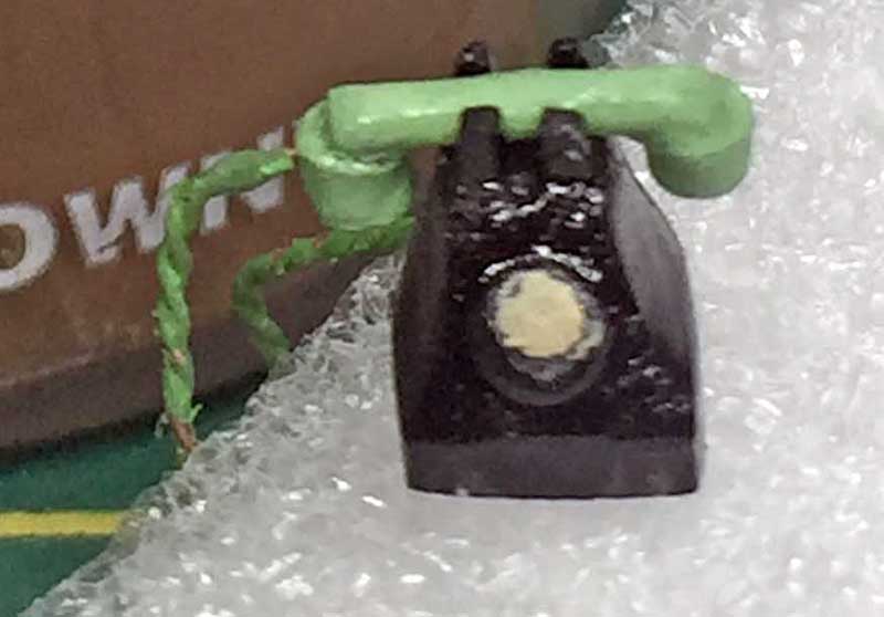 Pièce de maquette du tracteur Fordson 7V peinte en noir avec fil vert posée sur papier bulle