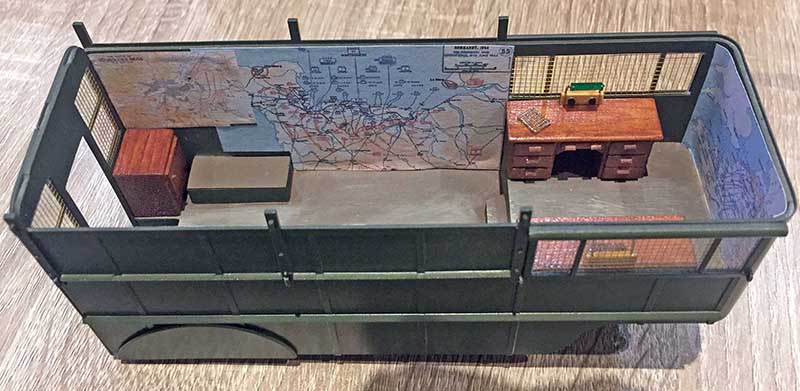 Maquette d'aménagement intérieur de fourgon militaire avec bureau, cartes murales et coffre en bois