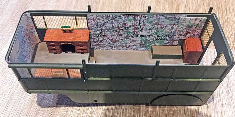 Aménagement intérieur de la caisse avec bureau, coffres et carte d'état-major murale