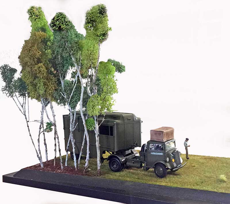 Diorama du tracteur Fordson 7V kaki avec remorque sous des arbres et figurine