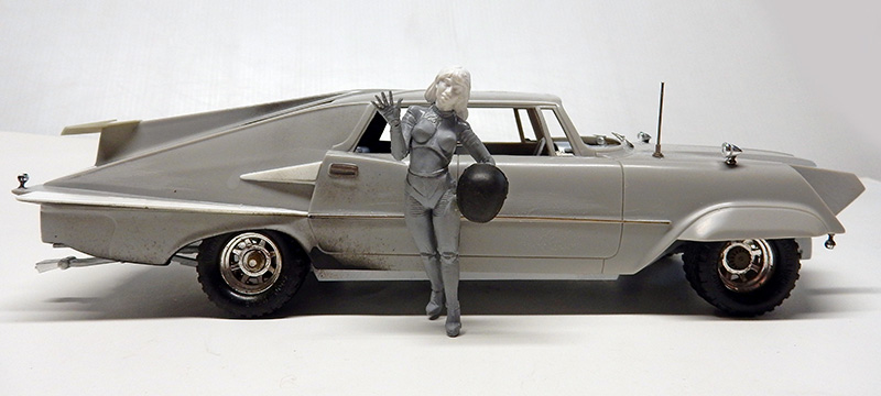 Maquette de voiture futuriste grise avec figurine de policière tenant un casque
