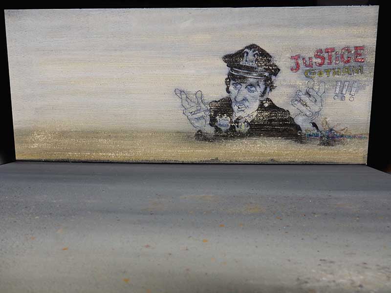 Décor mural peint figurant un policier et l'inscription « Justice Gotham » au-dessus d'un sol gris