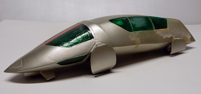 Maquette de véhicule futuriste argenté aux vitres vertes, carrosserie effilée de type aérodynamique