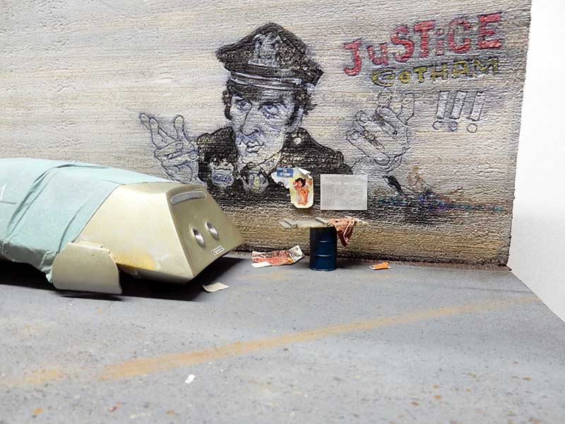 Maquette de diorama urbain avec graffiti d'un policier et inscription « Justice Gotham » sur un mur