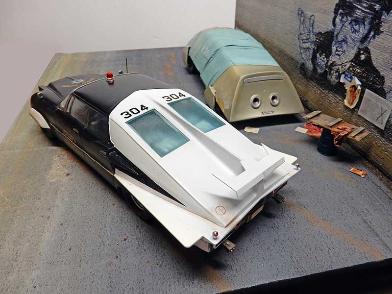 Maquette de voiture de police futuriste numérotée 304 en cours de montage sur l'établi