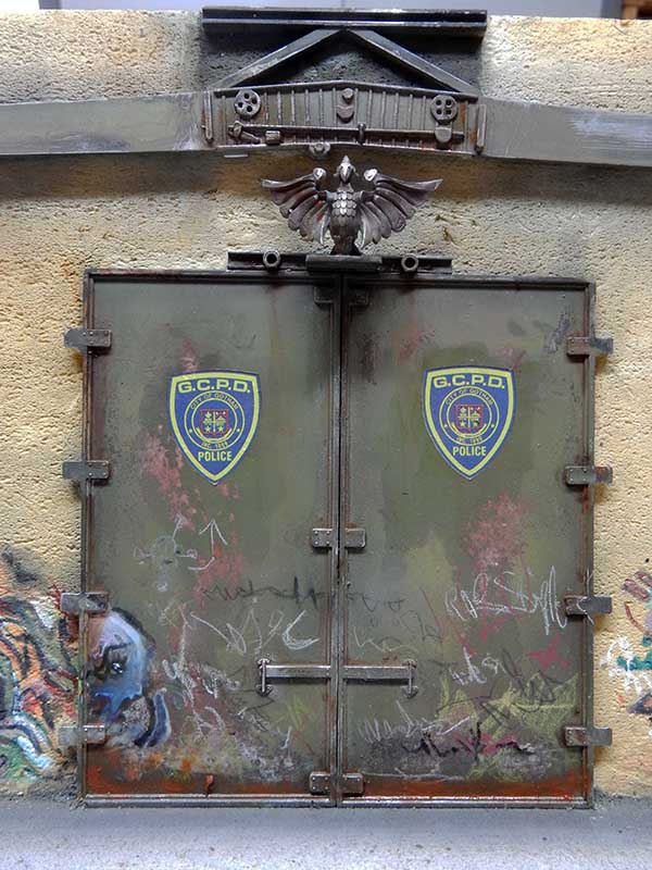 Portes blindées vert-de-gris d'un poste de police GCPD patiné, surmontées d'un aigle sculpté