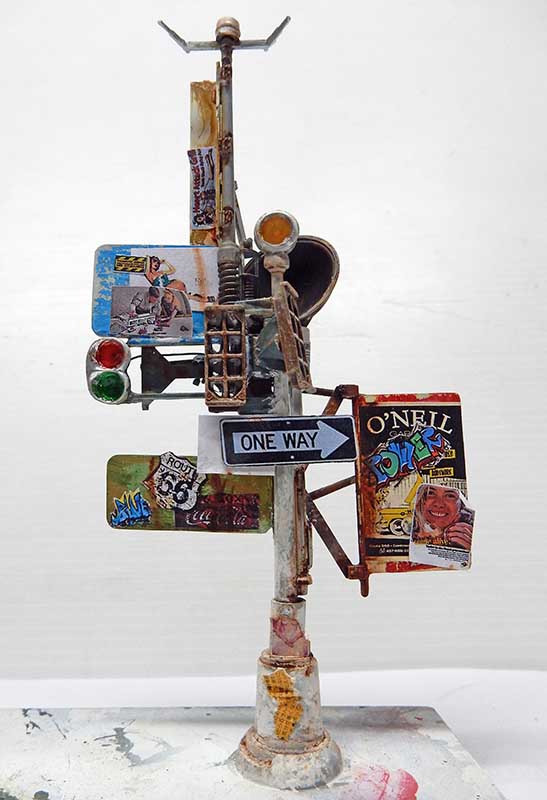 Maquette de feu de signalisation urbain vieilli couvert d'affiches, panneaux One Way et graffitis
