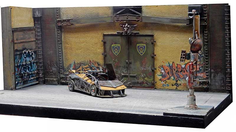 Diorama de voiture de police futuriste devant un poste aux murs couverts de graffitis