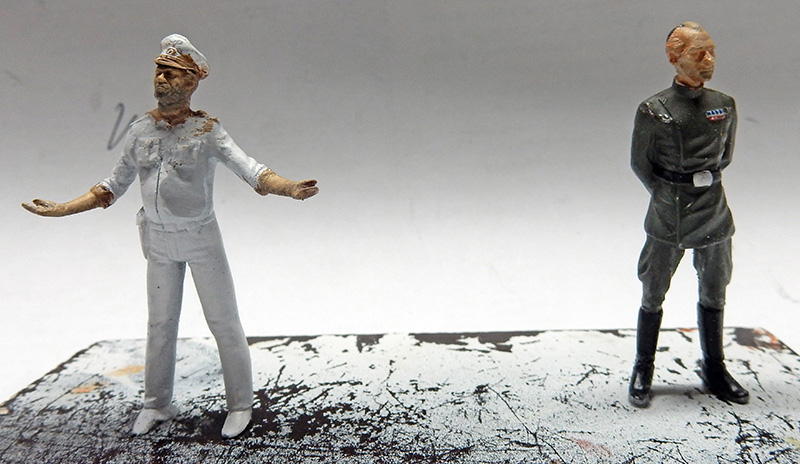 Deux figurines d'officiers peintes, l'une en uniforme blanc bras écartés, l'autre en gris
